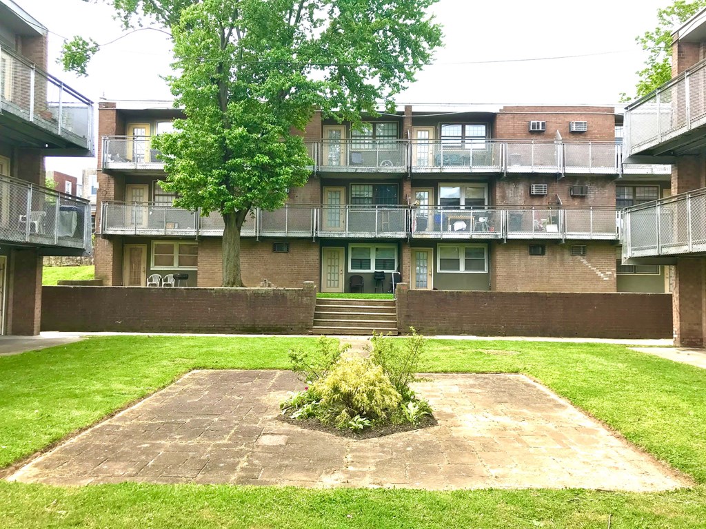 the courtyard of an apartment building with grass and a tree