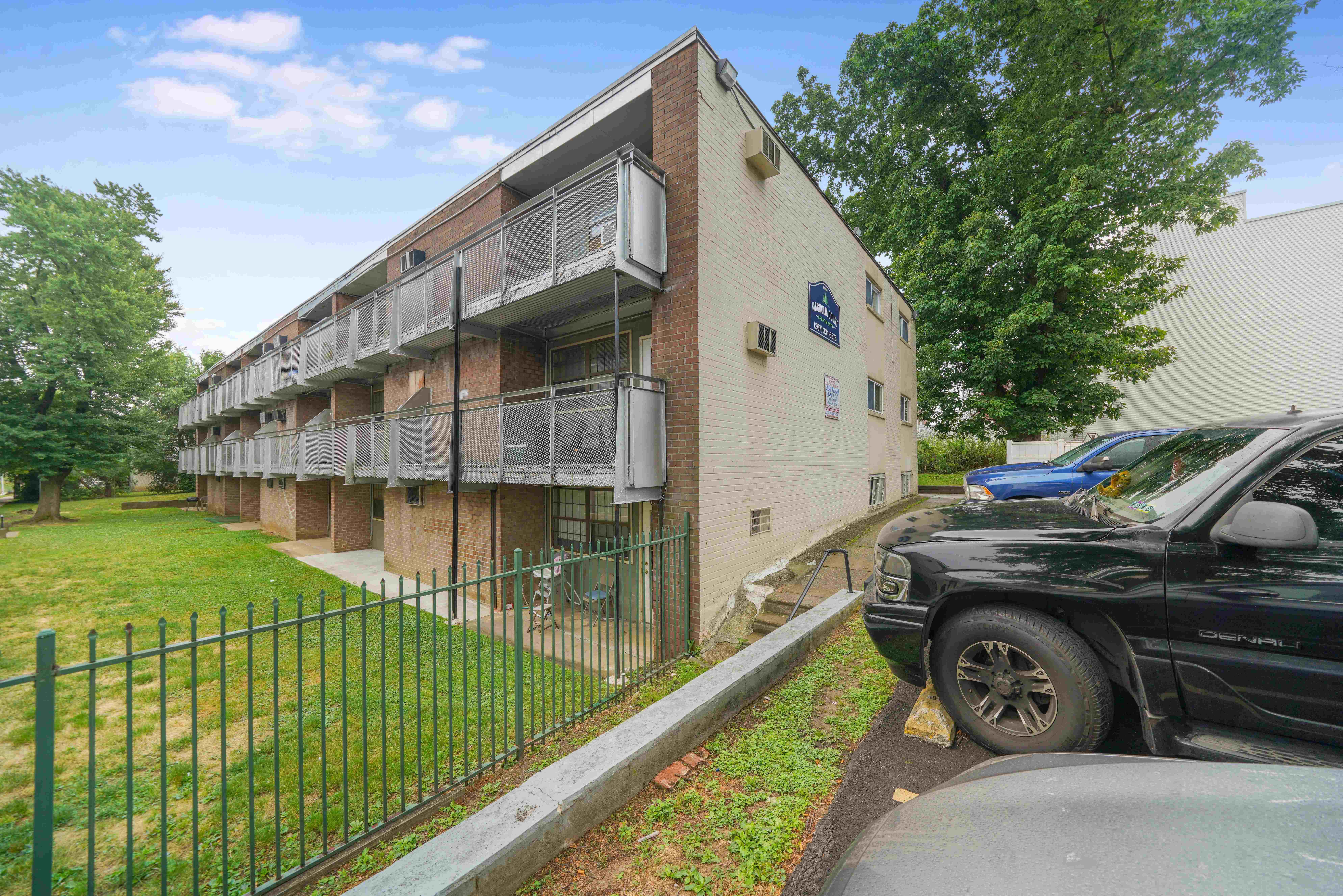 front view of an apartment building with cars parked in front