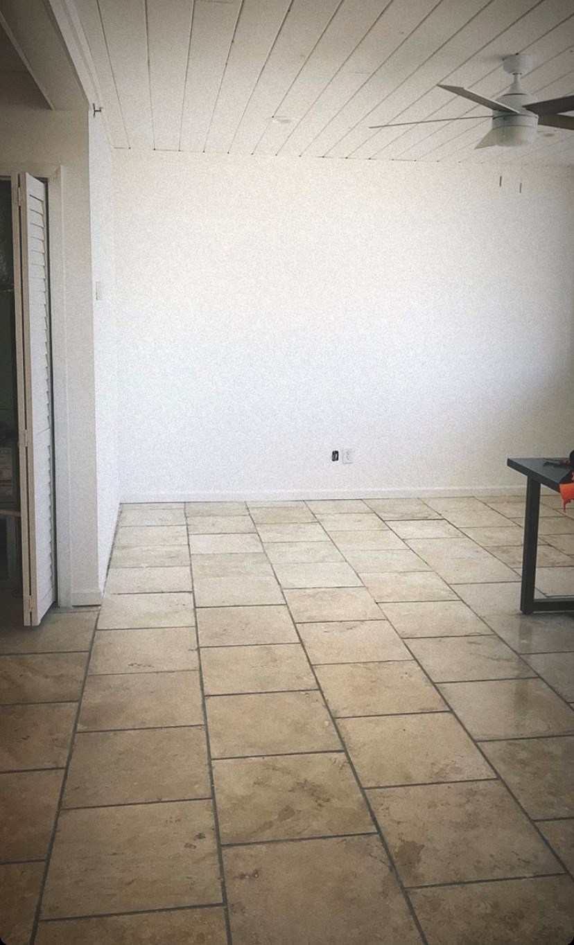 an empty room with a white wall and tiled floor