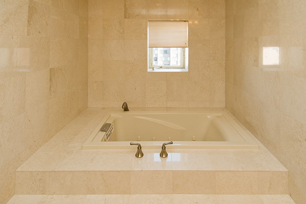 a large white bath tub in a bathroom with a window