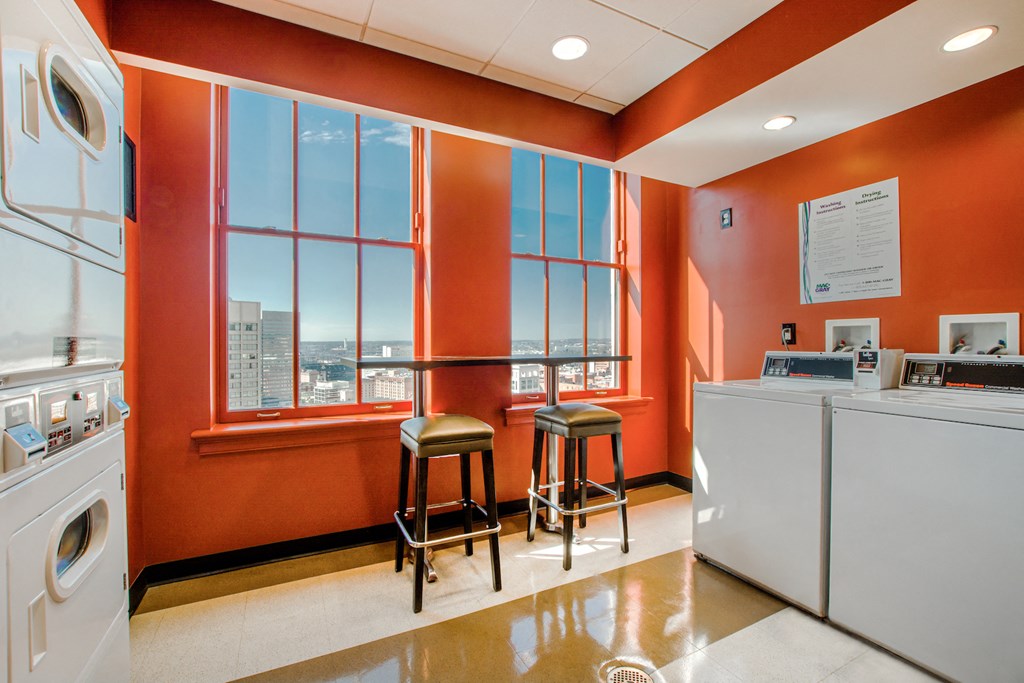 a laundry room with two stools and a window and a washing machine and was