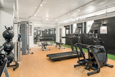 A gym with a variety of equipment including treadmills, weights, and exercise machines.