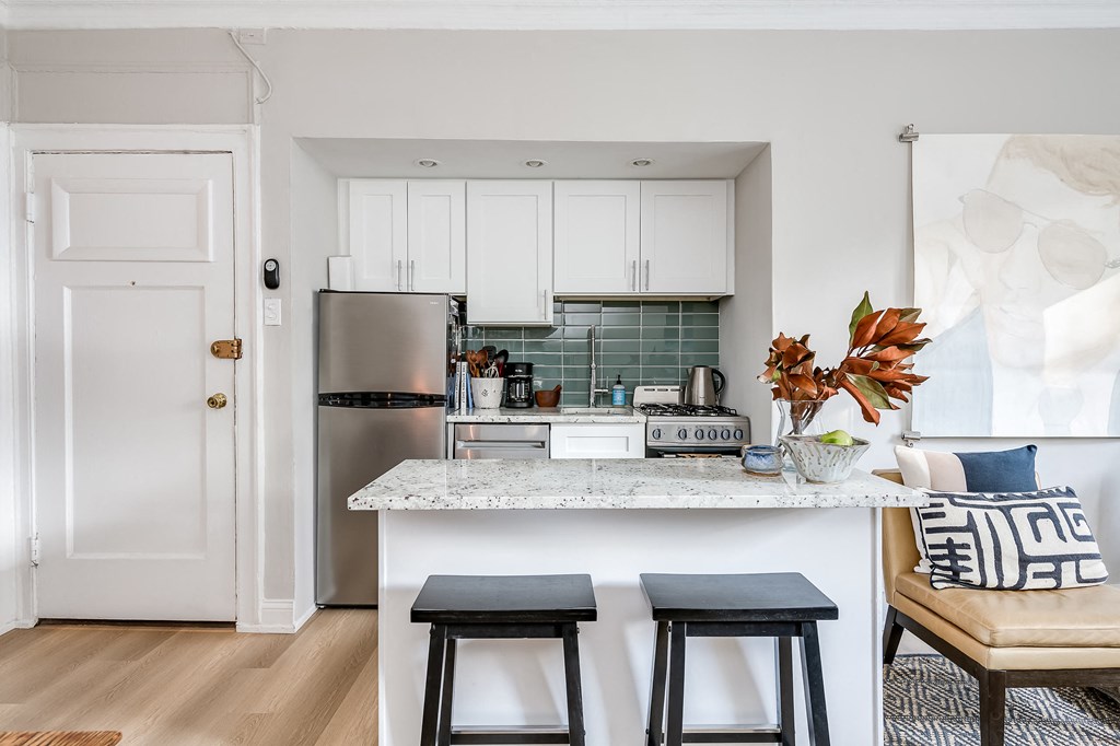 a kitchen with white cabinets and a counter top with two stools