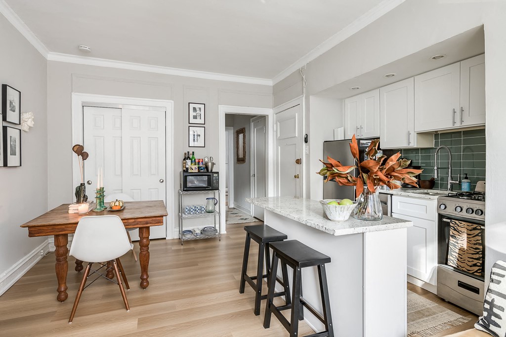 a kitchen and dining room with white cabinets and a marble counter top