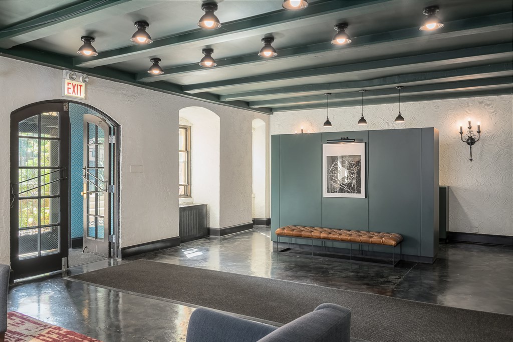 a lobby with a couch and a door and lights on the ceiling