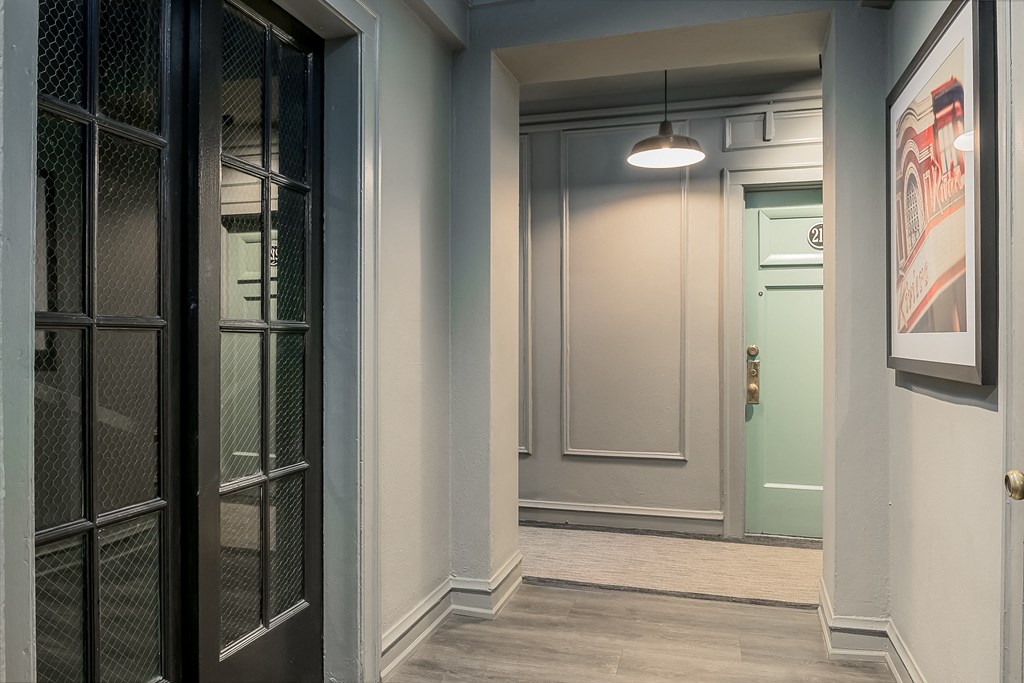 a hallway with glass doors and a door to a room with a green door