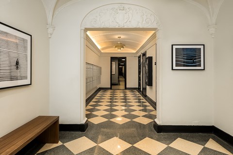 a hallway in a building with a checkered floor and a bench