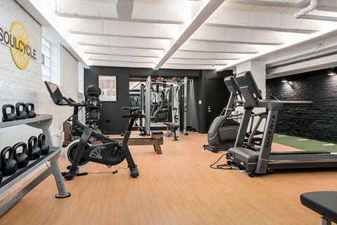 A gym with a variety of equipment including a rowing machine, a bench press, and a leg press.
