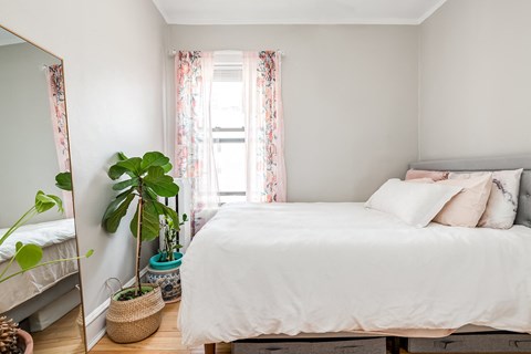 a bedroom with a bed and a mirror and a plant