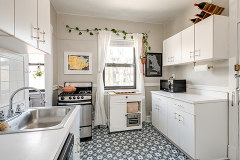 a kitchen with white cabinets and a sink and a window