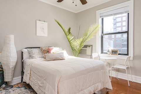 A bedroom with a white bed and a white chair.