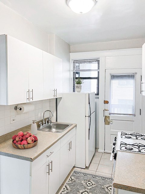 A kitchen with white cabinets and a black and white rug.