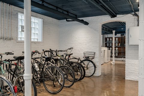 A room with white walls and a white brick wall with bicycles parked against it.