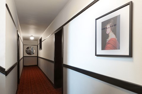 a hallway with a picture of a woman on the wall and a red carpet