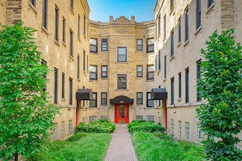 a brick building with a red door and a walkway