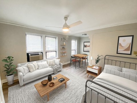 A living room with a white couch, a wooden coffee table, and a bed with a white comforter.