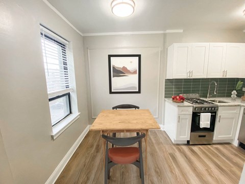 A kitchen with a table and chairs in front of a window.