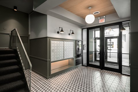 a lobby with a staircase and a door to a building with mailboxes