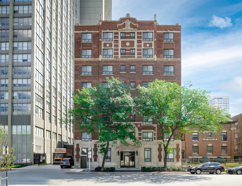 a tall brick building with trees in front of a street