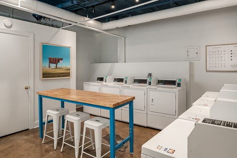 a laundry room with a table and stools and washing machines