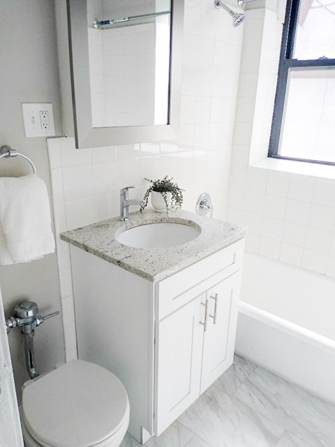 A white bathroom with a toilet, sink and mirror.