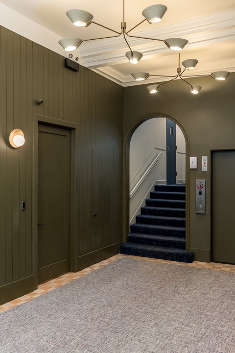 A hallway with a staircase and a mirror on the wall.