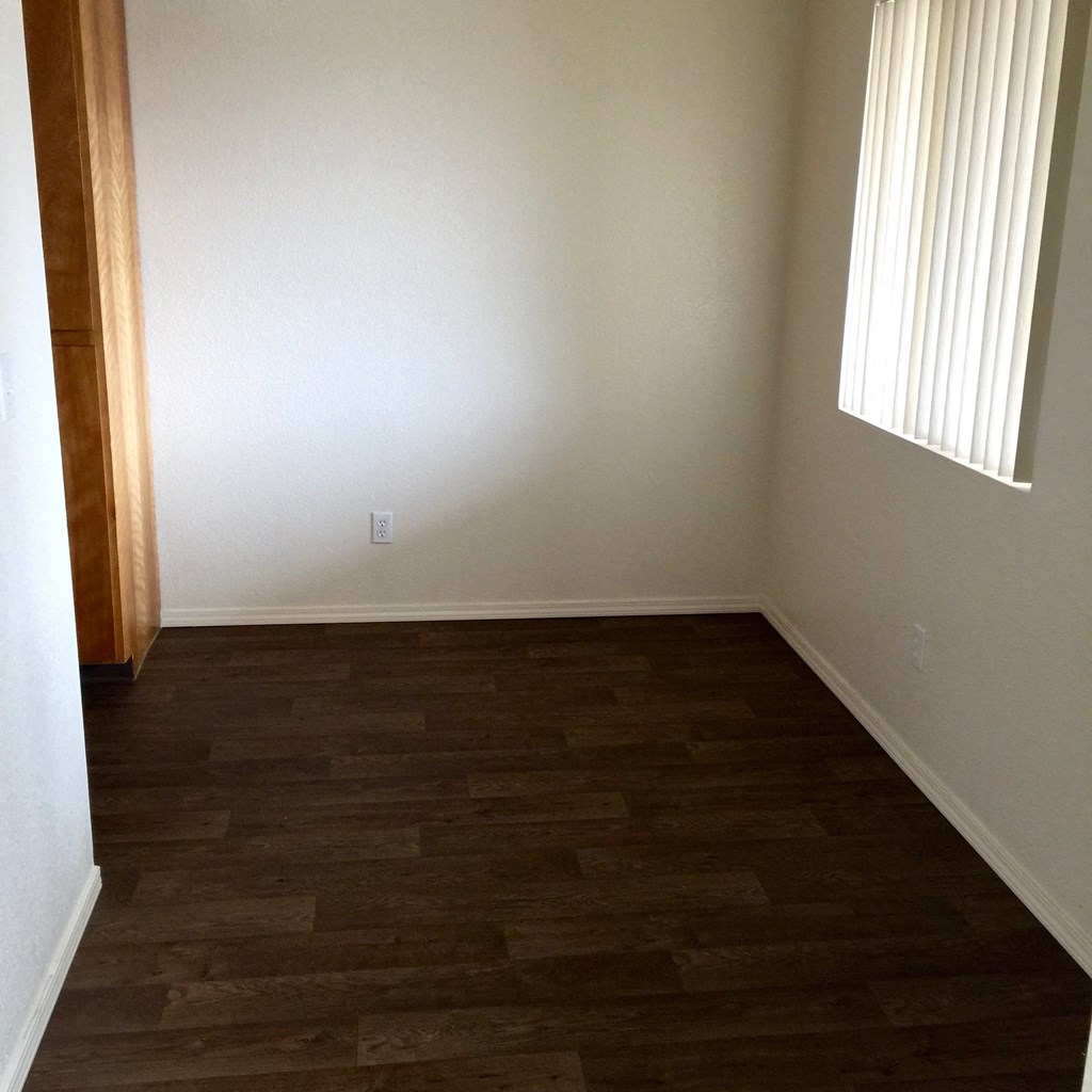 an empty room with wooden floors and a window