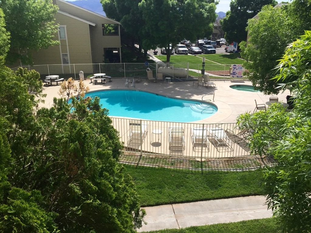 an aerial view of a swimming pool with chairs and a fence around it