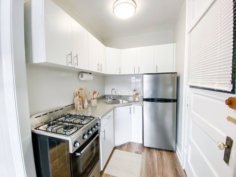 A kitchen with a stove, refrigerator, and cabinets.