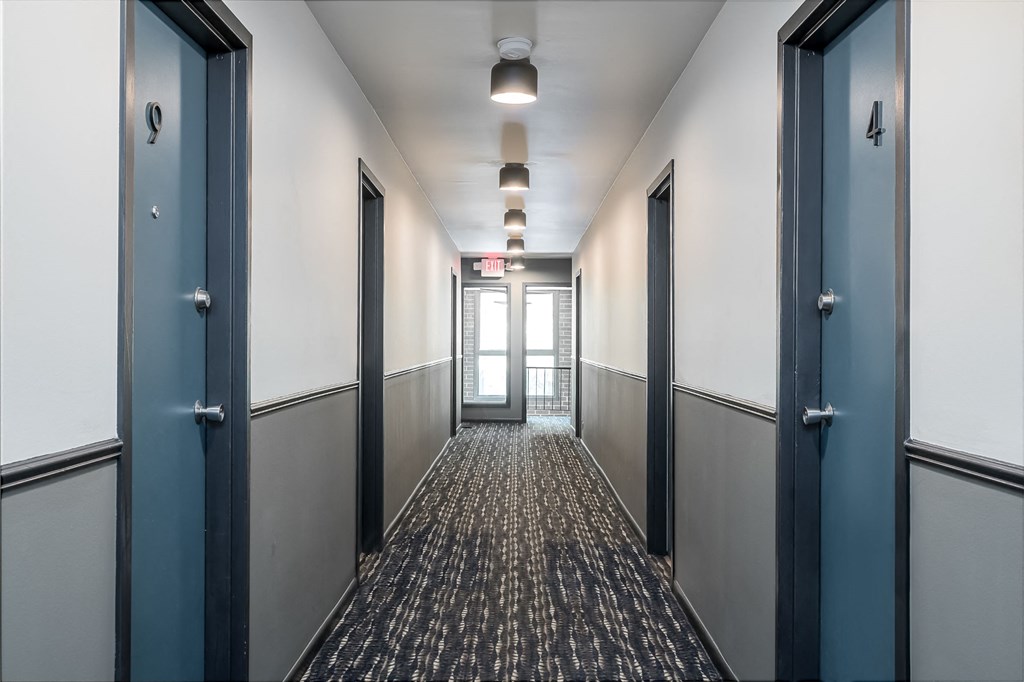 a hallway with blue doors and white walls and a carpeted floor