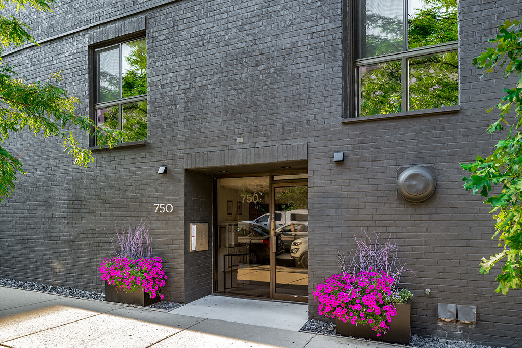 the front of a brick building with a door and flowers