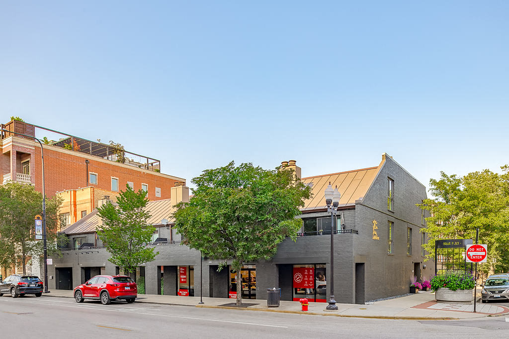 the corner of a city street with buildings and a red car
