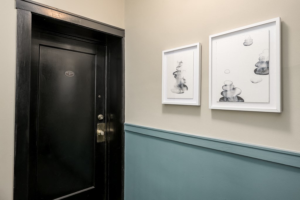 two paintings hanging on a wall next to a black door