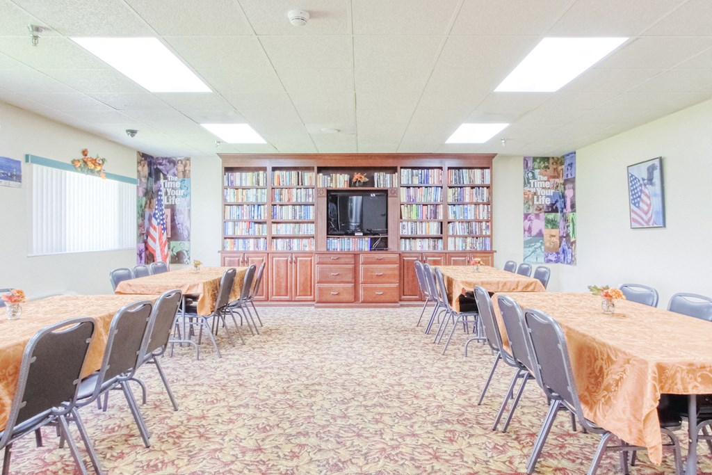 VSCII-Library large community room with tables, chairs, TV, and many shelves of books
