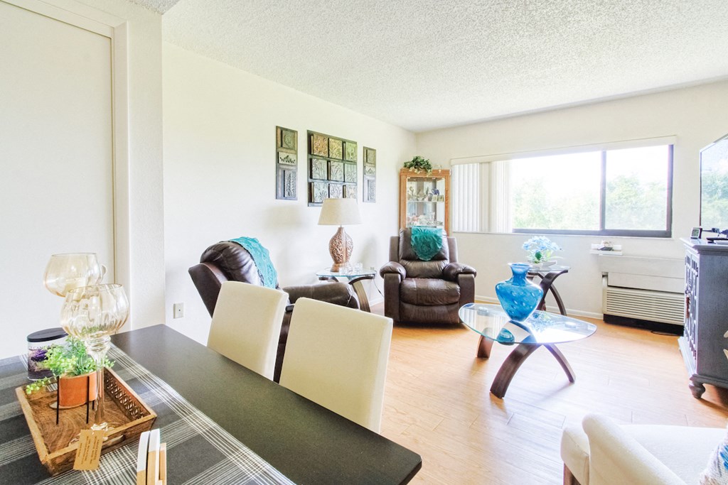 model living room with hardwood-style flooring, large windows, and model furniture