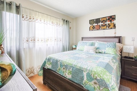 model bedroom with large window and hardwood-style flooring