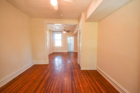 an empty living room with wood floors and white walls