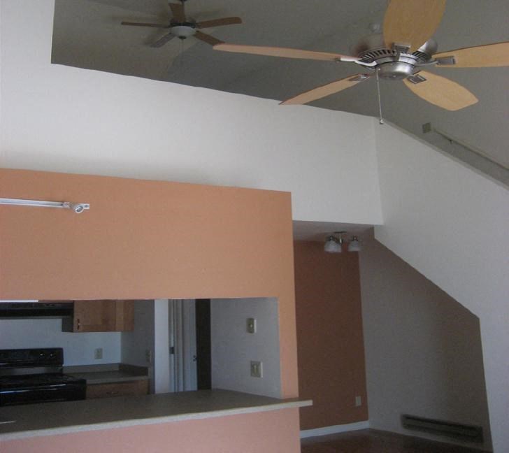 a living room with a ceiling fan and a kitchen