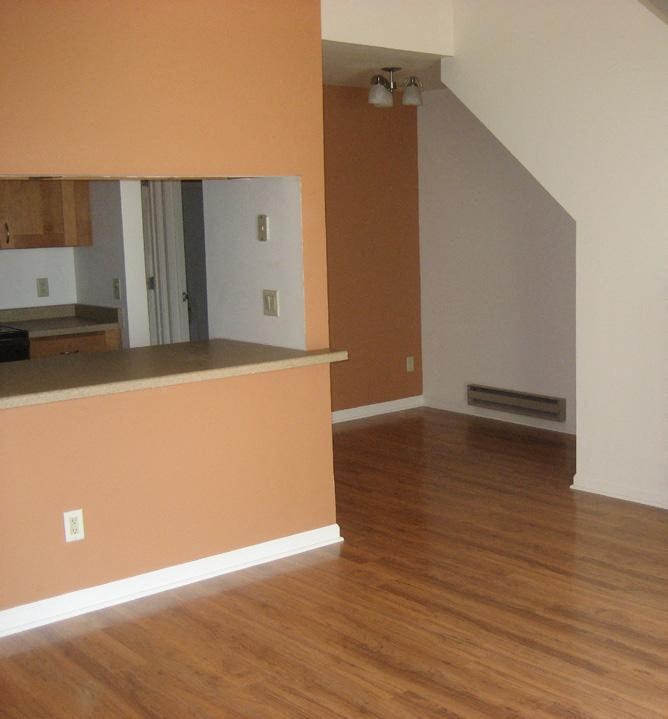an empty living room and kitchen with a wood floor