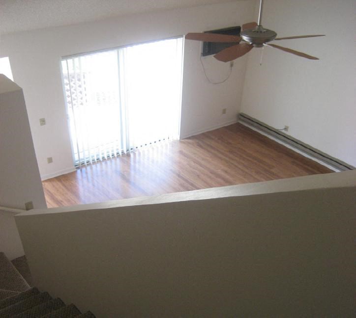 an empty living room with a ceiling fan