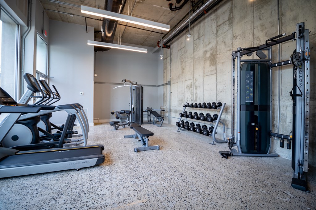 a gym with weights and other exercise equipment in a building with cement walls