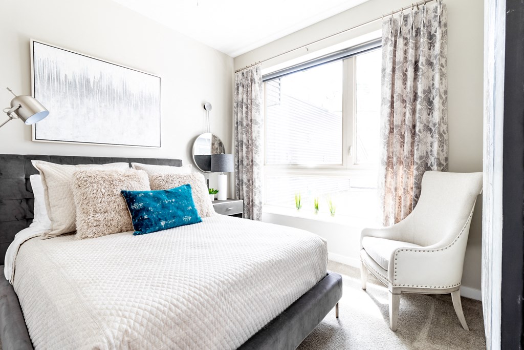 a bedroom with a bed and a chair and a window