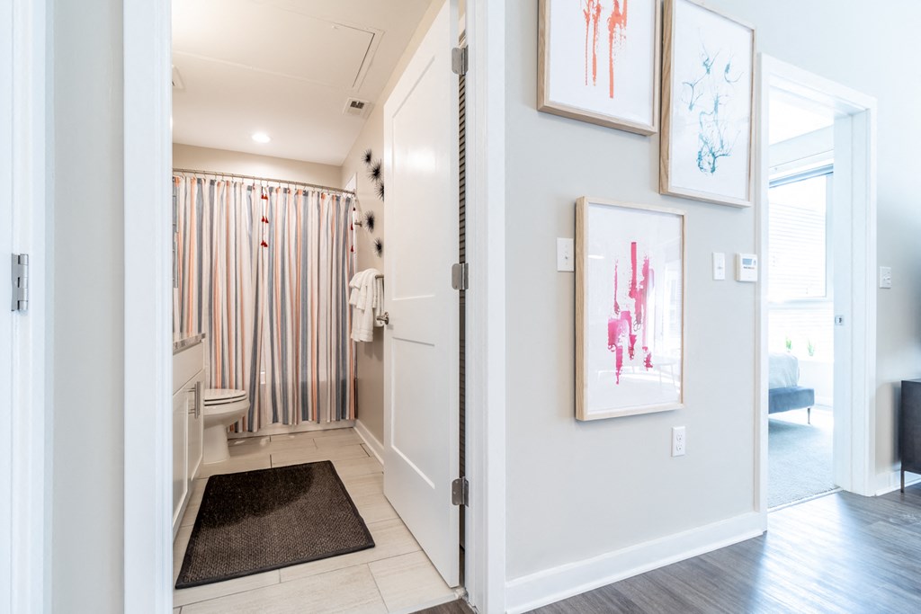 a hallway with pictures on the wall and a door to a bathroom