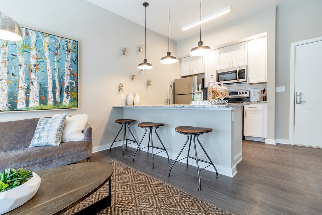 a living room and kitchen with a bar and stools