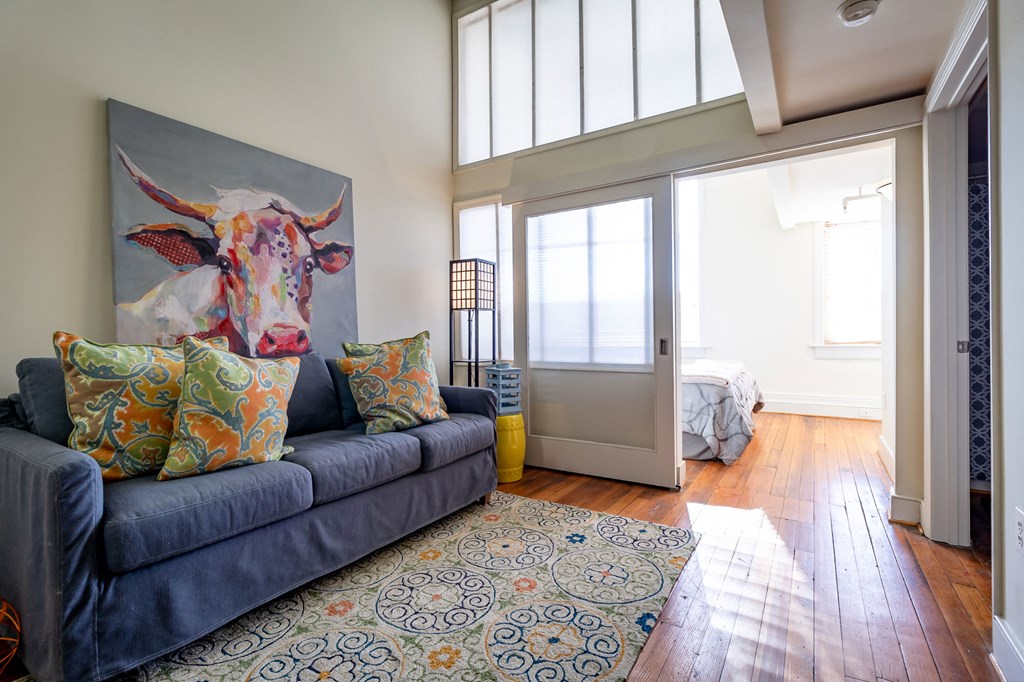 a living room with a couch and a rug and a door to a bedroom