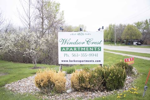 a sign for windsor creek apartments is shown in front of a garden
