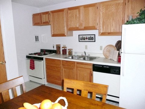 a kitchen with white appliances and wooden cabinets and a wooden table