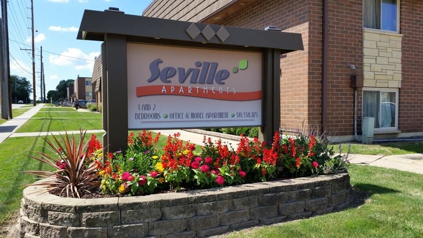 Entrance sign. Nice flower bed at Seville Apartments in Iowa City, IA - Photo Gallery 1