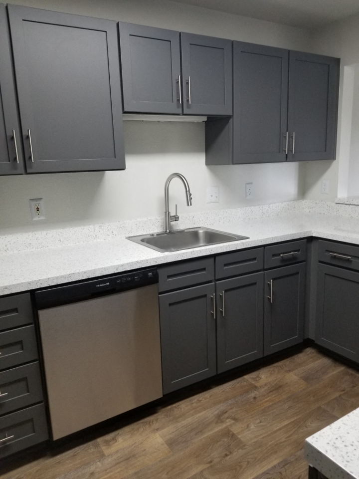 an empty kitchen with black cabinets and a stainless steel sink