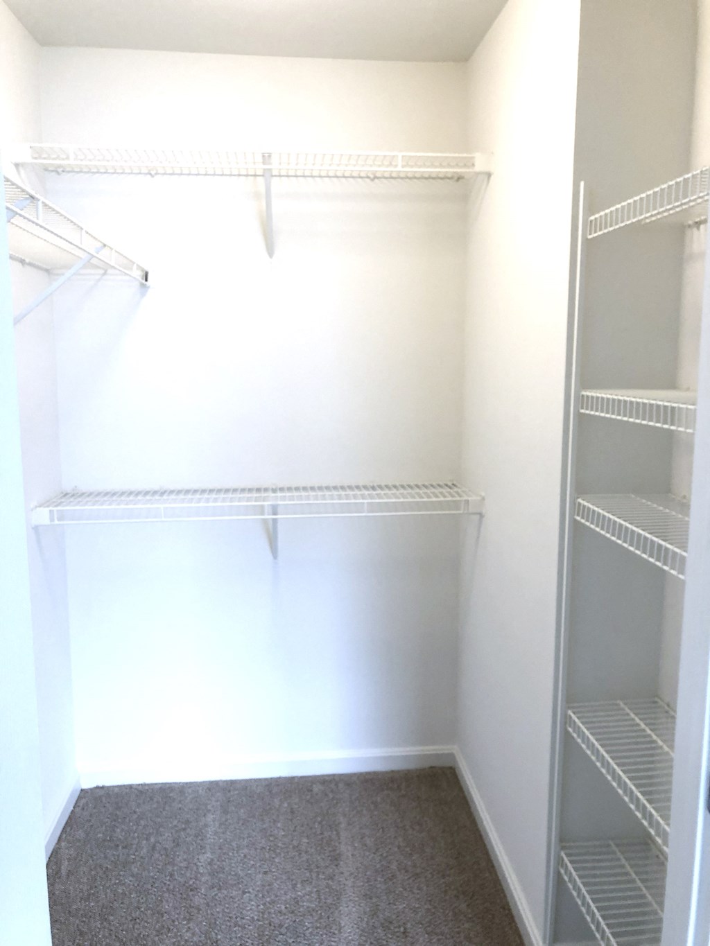 a walk in closet with empty shelves and white walls